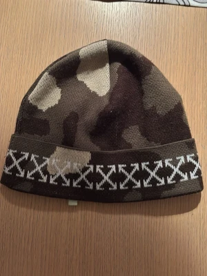 Offwhite mössa - Säljer en snygg kamouflagefärgad off white mössa som inte är använd. Mössan är stickad och har en klassisk passform som passar perfekt till höst och vinter. Materialet känns mjukt och bekvämt, perfekt för kalla dagar. Kontakta vid köp, pris går att diskutera!🔥🔥