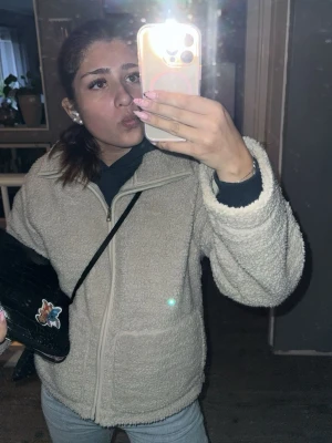 Beige teddyjacka med dragkedja - Mysig beige teddyjacka med dragkedja framtill och hög krage. Jackan har en avslappnad passform och är gjord i fluffigt teddy-material som håller dig varm. Perfekt för lager på lager och enkel att matcha med olika outfits. den har lite smink på kragen men tvättar den ju såklart innan jag skickar iväg den