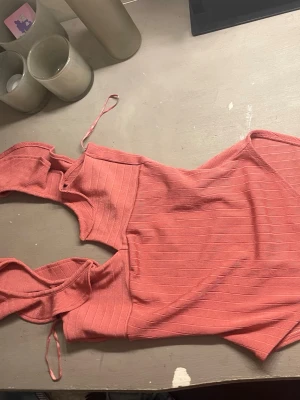 Rosa ribbad body med knytband - Trendig rosa body med ribbad struktur och smala axelband som knyts. Materialet är stretchigt och följsamt, vilket ger en snygg passform. Perfekt för party eller häng. Inga synliga loggor eller märken.
