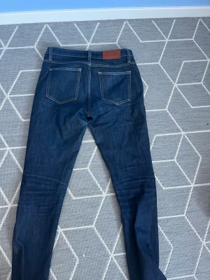Acne studios byxor - Snygga mörkblå jeans från Acne Studios. Jeansen har en rak passform och är tillverkade i bomull. Väldigt sköna och sitter perfekt!