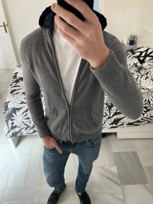 Grå stickad cardigan med huva - Säljer en väldigt snygg stickad cardigan med avtagbar huva i storleken 13-14 men skulle säga att det är en XS-S i herrstorlek. ——————————————————————————                   📐| Storlek: XS- S                                                    👖| Märke: Massimo Dutti                                      🔎 | Skick: Mycket bra                                            ✍🏻 | Skriv om du har några frågor 