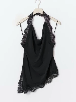 Svart spetsdetaljerad linnetopp - Snygg svart linnetopp med tunna axelband och vacker spets runt halsringning och nederkant. Toppen har en draperad front och asymmetrisk skärning som ger en trendig look. Perfekt att styla med jeans eller kjol. Aldrig använd