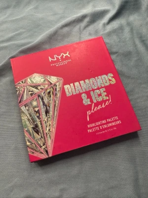 NYX Diamonds & Ice Highlighterpalett - Säljer en färgstark highlighterpalett från NYX Diamonds & Ice. Paletten innehåller fyra skimrande nyanser i guld, champagne, brons och koppar. Förpackningen är rosa med holografiska detaljer och diamantmotiv. Perfekt för att skapa glow och highlighta ansiktet.Använd en gång