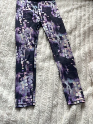 Mönstrade leggings från H&M Sport - Säljer ett par snygga leggings från H&M Sport med abstrakt mönster i lila, svart och vitt. De har hög midja och stretchigt material som passar perfekt till träning eller chill. Supersköna och trendiga för dig som gillar färg och mönster!