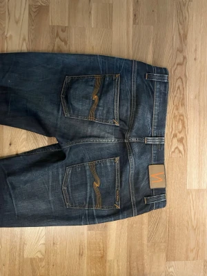 Nudie Jeans Grim Tim – sjuka fades - Säljer ett par Nudie Jeans Grim Tim i riktigt snyggt skick med naturligt slitna fades. Byxorna har utvecklat några av de sjukaste fadesen – perfekt för dig som gillar autentisk denim med karaktär.  👖 Modell: Grim Tim (slim straight fit) 🎨 Färg: Mörkblå denim med naturliga whiskers & honeycombs ✨ Skick: Bra skick med snygg patina och slitningar från användning 🧵 Klassiska Nudie-detaljer med signaturstygn på bakfickorna  Hör av dig vid frågor eller om du vill ha fler bilder 🙂 
