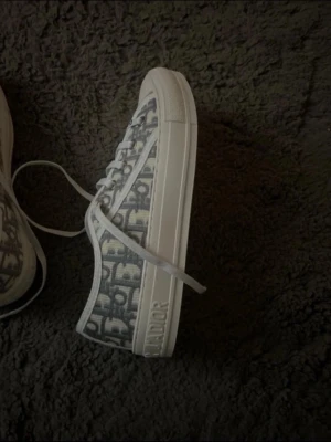 Dior Oblique låga sneakers - Snygga låga sneakers från Dior med det klassiska gråa Oblique-mönstret på textil och vita detaljer i gummi. Skorna har vita snören och en tjock vit sula med Dior-logga på sidan. Perfekta för dig som vill ha en exklusiv och trendig look.