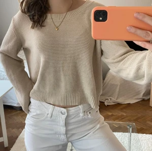Beige stickad croppad tröja - Säljer en tunn, beige stickad tröja med croppad passform och rund halsringning. Tröjan har långa ärmar och ribbade muddar vid ärmslut och nederkant. Perfekt att styla med höga jeans för en avslappnad look nu till våren💐 
