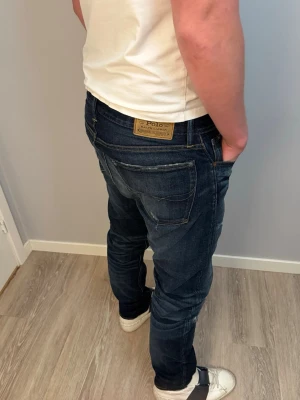 Polo Ralph Lauren Jeans - Snygga mörkblå slim fit jeans från Polo Ralph Lauren med klassiska fem fickor och slitna detaljer. Storlek: W32, L34. Måtten på byxorna är: Längd: 112 cm Bredd lår: 27 cm Midja: 42 cm  Benöppning: 18 cm