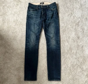 Neuw jeans - Otroligt feta mörkblå Neuw jeans i slim fit med klassisk femficksdesign och diskreta snygga detaljer. Super bekväma, snygga och stilrena jeans som jag kan garantera att du kommer bli nöjd med. Jeansen har normal midja, slim passform och är tillverkade för extra komfort. Perfekta för dig som gillar en stilren och modern look. Modellen heter Iggy och är slim fit i storleken 30/32. Badgen där bak är i svart mocka. 