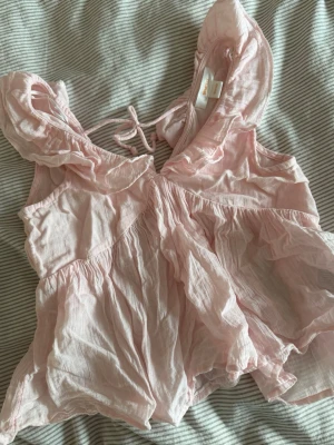 Ljusrosa volangblus - Supersöt ljusrosa blus med volangdetaljer och knyt i ryggen. Blusen är inte struken, men kan göras vid köp🩷