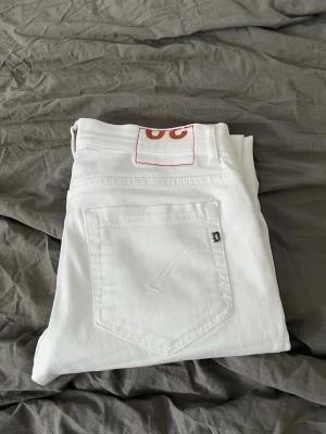 Vita skinny jeans från dondup  - Säljer ett par vita skinny jeans från dondup med klassisk femficksdesign och diskret logga på bakfickan. Jeansen har en smal passform och är tillverkade i ett mjukt bomullstyg. Perfekta för dig som vill ha en clean och stilren look. Köpta för 1,6 och har använt endast 3 gånger