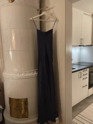 Mörkblå långklänning  - Elegant mörkblå långklänning med smala axelband och öppen rygg. Klänningen har en slimmad passform upptill och faller snyggt längs kroppen. Perfekt för festliga tillfällen och bal. Helt oanvänd och fortfarande i orginal förpackning🌟 köpt för 1700kr säljer för 550kr!!