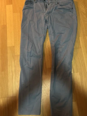 Grå chinos med raka ben från Ralph Lauren - Snygga grå chinos med raka ben och klassisk passform. Byxorna har två framfickor och två bakfickor med knappdetalj. Tillverkade i ett mjukt och bekvämt bomullsmaterial som passar perfekt till en avslappnad stil.
