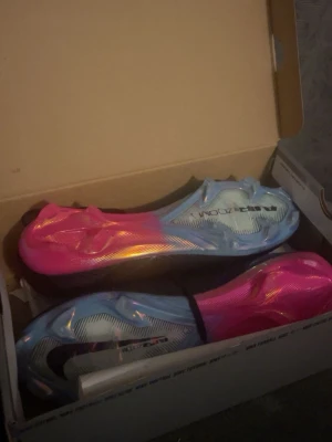 Nike Mercurial fotbollsskor svart/blå/rosa - Säljer ett par Nike Mercurial fotbollsskor med svart ovandel, vita och rosa detaljer samt en sula i blått och rosa. Har använt de en gång säljer för att de är för stora.😁