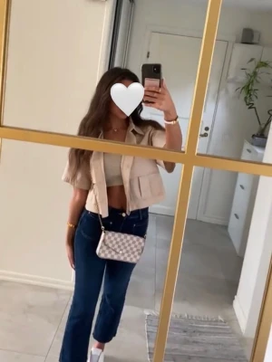 Beige cropped overshirt från H&M - Snygg beige overshirt från H&M med croppad passform och stora fickor framtill. Skjortan har klassisk krage och knäppning med knappar. Perfekt att styla över ett linne eller t-shirt för en trendig look.