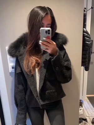 Meotine kappa  - Snygg svart pälsjacka med bred, fluffig krage och knäppning framtill. Meotine jacka storlek s/m