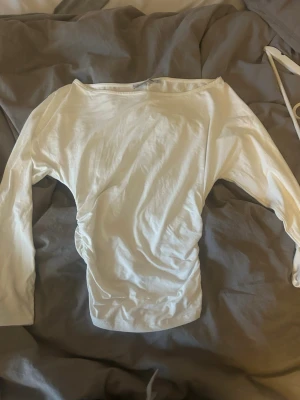 Vit långärmad topp med båtringning - Säljer en enkel och stilren vit långärmad topp med båtringning. Toppen har en figurnära passform och är tillverkad i mjukt bomullsmaterial. Perfekt att matcha med jeans eller kjol för en clean look.
