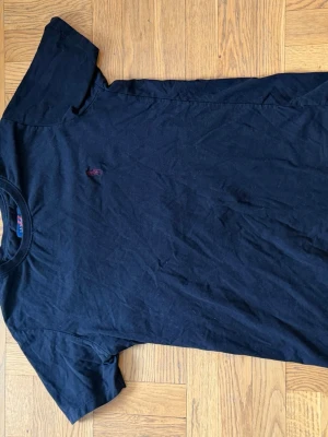 Svart t-shirt från U.S polo Assn - Klassisk svart t-shirt från U.S polo Assn  med rund hals och korta ärmar. T-shirten har en liten röd broderad logga på bröstet och är gjord i mjuk bomull för en skön känsla. Perfekt basplagg till garderoben.