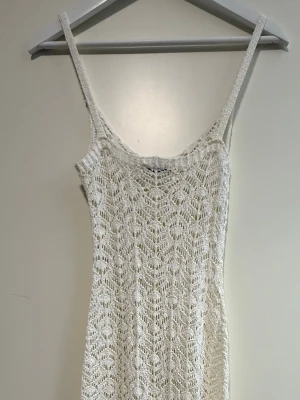 Virkad klänning  - Säljer en vit virkad klänning med smala axelband och ett detaljerat spetsmönster. Klänningen har en kroppsnära passform och är perfekt för varma dagar. Materialet är mjukt och luftigt, vilket ger en bohemisk och trendig känsla.