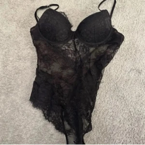 Svart spetsbody med tunna axelband - Snygg svart body i genomskinlig spets med tunna justerbara axelband och vadderade kupor. Figurnära passform och vacker spetsdetalj över hela plagget. Perfekt för att känna sig extra fin. Super trendig spets body från hm, säljer då kuporna helt enkelt blivit för små för mig. As snygg och sitter som en smäck. Perfekt på fest kostade runt trehundra kroner någon stans ny, säljer runt samma pris pågrund av efterfrågan storlek 75b ❤️