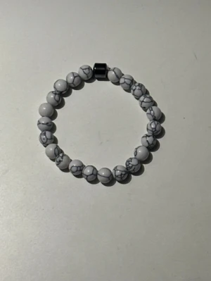 Vitt pärlarmband med marmormönster - Snyggt armband med vita pärlor och grått marmormönster. Elastiskt band gör det enkelt att ta på och av. Passar perfekt för dig som gillar stilrena accessoarer med en twist.