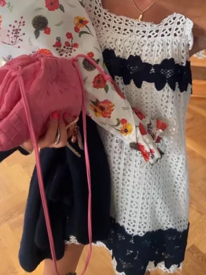 Vit spetsklänning med svarta detaljer - Säljer en söt vit klänning i spets med breda svarta spetsband över byst och nederkant. Klänningen har fyrkantig ringning, volangärmar och är fodrad. Fint skick! Storlek 38 men är mer som 36 skulle jag säga❤️