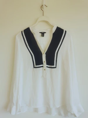 Blus i marin stil - Blus i marin stil med guldfärgade knappar. Känns som storlek 38 eller 40. Luftigt tyg, förmodligen polyester. 