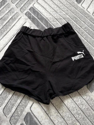 Svarta shorts Puma - Säljer ett par svarta shorts Puma med elastisk midja och fickor på sidorna. Puma-logga i vitt på vänster ben. Perfekta för träning eller chill. Mjukt och bekvämt material. Not real puma
