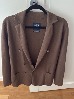 Boggi Milano merino kofta - Stilren brun kofta från Boggi Milano i extrafin merinoull. Dubbelknäppt modell med fyra silverfärgade knappar framtill och två stora fickor. Klassisk krage och mjuk, stickad känsla som ger en avslappnad men ändå dressad look. Nypris ca 7 tusen 