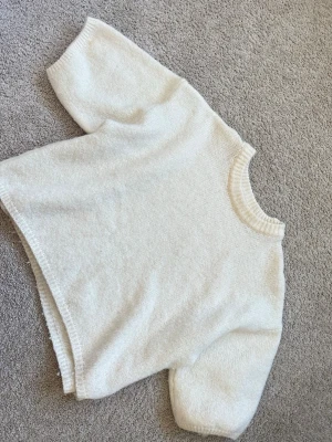 Krämvit stickad tröja med boxy fit - Mysig krämvit kortärmad stickad tröja med avslappnad boxy passform och ribbade muddar vid hals, ärmslut och nederkant. 