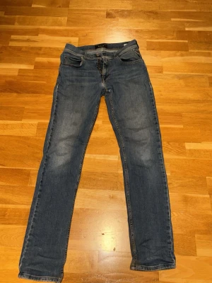 Blå Replay slim fit jeans  - Säljer ett par klassiska blå slim fit jeans från Replay. Jeansen har fem fickor, normalhög midja och snygga slitningar på låren. Materialet är mjukt denim med stretch för extra komfort. Perfekta till en avslappnad stil. Har blivit lite slitna men inga hål. Nypris cirka 700-1000kr. 