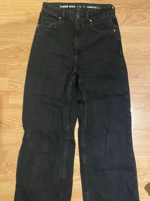 Bik Bok tower wide svarta jeans 28/32 - Säljer ett par svarta vida jeans med hög midja i superskick. Jeansen har hög midja, fem fickor och raka, vida ben. Klassisk knappgylf och bälteshällor. Perfekta för en avslappnad och trendig look.