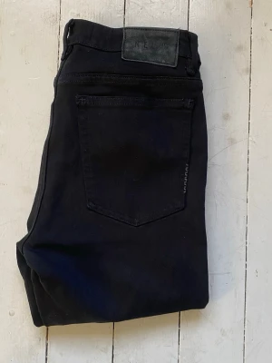 Svarta skinny jeans från Neuw  - Säljer ett par svarta skinny jeans från Nelly med klassisk femficksdesign och hög midja. Jeansen är i stretchigt material som sitter tight hela vägen ner. Perfekta till en avslappnad eller trendig look. Modellen är Bowery skinny black silk. Midjebredden är 35cm. Längden är 98cm. Smalben bredden är 16cm. 