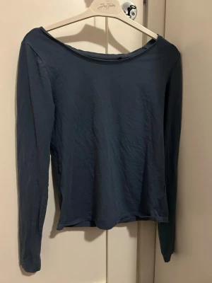 Dammblå långärmad topp från 157 - En enkel och stilren dammblå långärmad topp från 157. Tillverkad i mjuk bomull med lite stretch för skön passform. Rundad halsringning och normal passform gör den lätt att matcha till olika outfits. Tröjan är i storlek M.