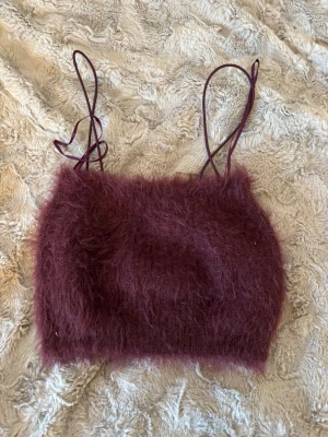 Vinröd fluffig linnetopp från Zara - Säljer en vinröd fluffig linnetopp från Zara med tunna axelband. Toppen har en mjuk och lurvig yta som ger en unik look och känns supermysig. Perfekt för dig som vill sticka ut med en trendig och cool topp. Det är en magtröja 💕