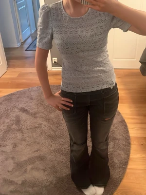 Ljusblå spetsblus med puffärm - Supersöt ljusblå topp i spets med puffärmar och rund hals. Figurnära passform och korta ärmar ger en trendig look. Perfekt att styla med jeans eller kjol för en fräsch outfit. Materialet är spets med fina detaljer.