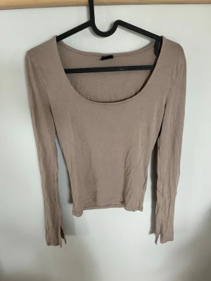 Gina Tricot Soft Touch beige långärmad topp - En enkel och stilren beige långärmad topp med rund, djup ringning. Toppen har en tight passform och är tillverkad i ett mjukt bomullsmaterial som känns skönt mot huden. Perfekt att matcha med jeans eller kjol för en clean look. Från gina tricot och deras soft touch kollektion som har väldigt skönt och lent material som sitter kroppsnära. Använd fåtal gånger. Pris kan diskuteras!🥰