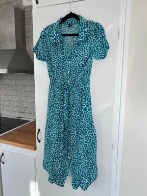 Blommig grönblå klänning, storlek S - En gullig blommig blå/grön klänning. Använd en handfull gånger, så i mycket fint skick!  Material: 100% viskos