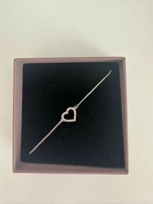 Silverarmband med hjärta från Edblad - Snyggt och stilrent armband i silver från Edblad med ett öppet hjärta i mitten, dekorerat med små gnistrande pärlor. Tunt kedjeband som ger en elegant look. Perfekt accessoar för att lyfta vilken outfit som helst.Helt ny och säljs för att jag har bytt till guld, pris kan diskuteras!🥰