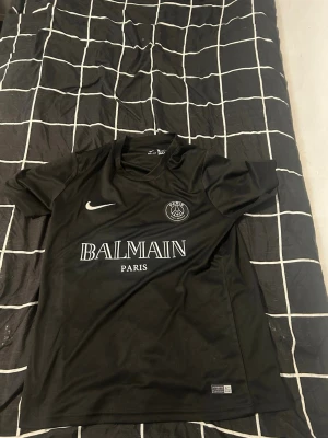 PSG x Balmain Matchtröja Svart – Strl M – Helt Ny & Autentisk - Säljer en helt ny och autentisk PSG x Balmain fotbollströja i storlek M. Tröjan är oanvänd och i perfekt skick. Stilren svart design med PSG-emblem, Nike-logga och Balmain Paris-tryck på framsidan. En exklusiv modell som passar både samlare och fotbollsfans.✔️ Storlek: M ✔️ Skick: Helt ny ✔️ 100 % autentisk ✔️ Färg: Svart ✔️ PSG x Balmain Edition ✔️ Nike Dri-FIT-material ✔️ Bekväm passform och hög kvalitet ✔️ Perfekt för både vardag och träning  💰 Pris: Kan diskuteras vid snabb affär.  📩 Skicka meddelan