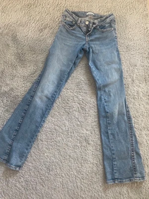 Jeans - Snygga ljusblå petite bootcut jeans från Gina Tricot i klassisk denim. Jeansen har fem fickor, låg midja och utsvängda ben. Säljer de eftersom att jag har växt ur de😊. 