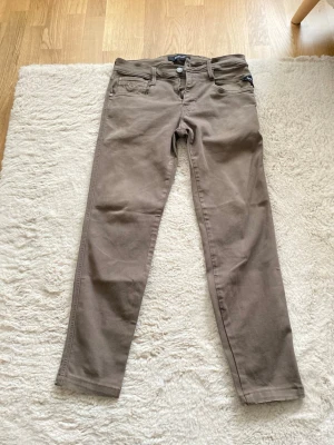 Bruna slim fit jeans från Replay  - Snygga bruna slim fit jeans från Replay med klassisk femficksdesign och normalhög midja. Jeansen har en stilren look och är tillverkade i ett mjukt bomullsmaterial med lite stretch för extra komfort. Perfekta för dig som gillar en enkel men trendig stil. Jag har också sytt den vid foten så att den sitter lite tight 