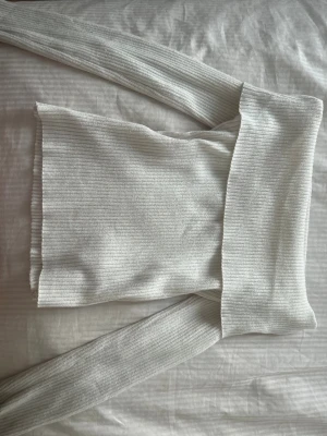Vit ribbad off shoulder stickad topp - Pris kan diskuteras💞 Trendig vit stickad topp med ribbad struktur och off shoulder-design. Långa ärmar och bred kant upptill ger en snygg och modern look. Perfekt att styla med jeans eller kjol för en cool outfit. 