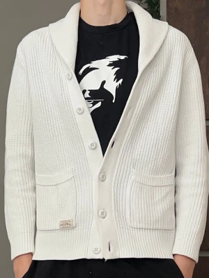 Extremt sällsynt limiterad kofta från Ralph lauren - Säljer en vit stickad kofta från Ralph Lauren med sjalkrage och knäppning framtill. Koftan har två framfickor och ribbade muddar. Perfekt för lager på lager och ger en clean look till din outfit. Koftan är sjukt sällsynt‼️har haft den i 2 år men har blivit för liten nu. Finns en liten fläck på ryggen men syns knappt vid användning 