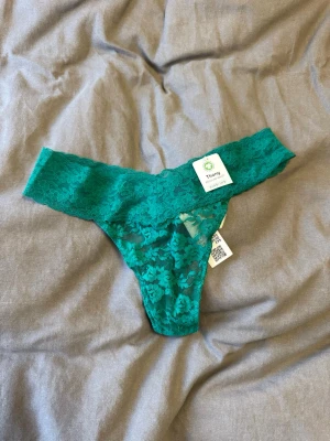 Gröna spetstrosor thong - Snygga gröna spetstrosor i thong-modell med bred spetskant och blommigt mönster. Trosorna är tillverkade i mjukt och stretchigt material som sitter bekvämt. Perfekta för dig som gillar en feminin och modern stil. Plomberade/ självklart oanvända!🌱