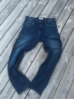 Mörkblå jeans från Alcott Denim - Snygga mörkblå jeans från Alcott Denim med klassisk femficksdesign och kontrastsömmar. Jeansen har en rak passform och är tillverkade i slitstarkt denimtyg. Perfekta för dig som gillar en tidlös och enkel stil.