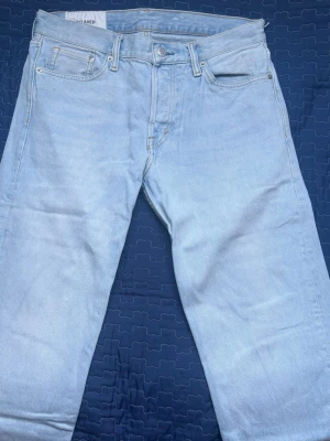 Ljusblå relaxed fit jeans - Säljer ett par ljusblå jeans i relaxed fit med raka ben och klassisk femficksmodell. Jeansen har en enkel design utan slitningar och är tillverkade i denim. Perfekta för en avslappnad och trendig stil.
