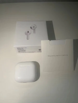 Apple AirPods med laddningsetui - Säljer ett par vita Apple AirPods med trådlöst laddningsetui. Hörlurarna har en stilren och kompakt design i blank plast och levereras med originalförpackning och tillbehör. Perfekta för musik, samtal och träning tack vare smidig Bluetooth-anslutning.