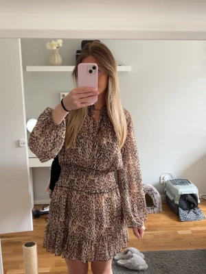 Leopardmönstrad klänning - Snygg kortklänning med leopardmönster och volangkant. Klänningen har långa, luftiga ärmar och markerad midja med resår. Knappt använd
