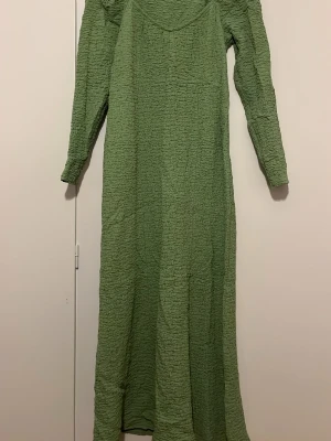 Ljusgrön långärmad långklänning - Långklänning i ljusgrönt med lång ärm och rynkad struktur. Klänningen har en rak och enkel siluett, tillverkad i ett stretchigt material som ger en bekväm känsla. Perfekt för dig som letar efter en midsommar, sommar klänning och för dig som gillar stilren och modern look. (Skriv för fler bilder)